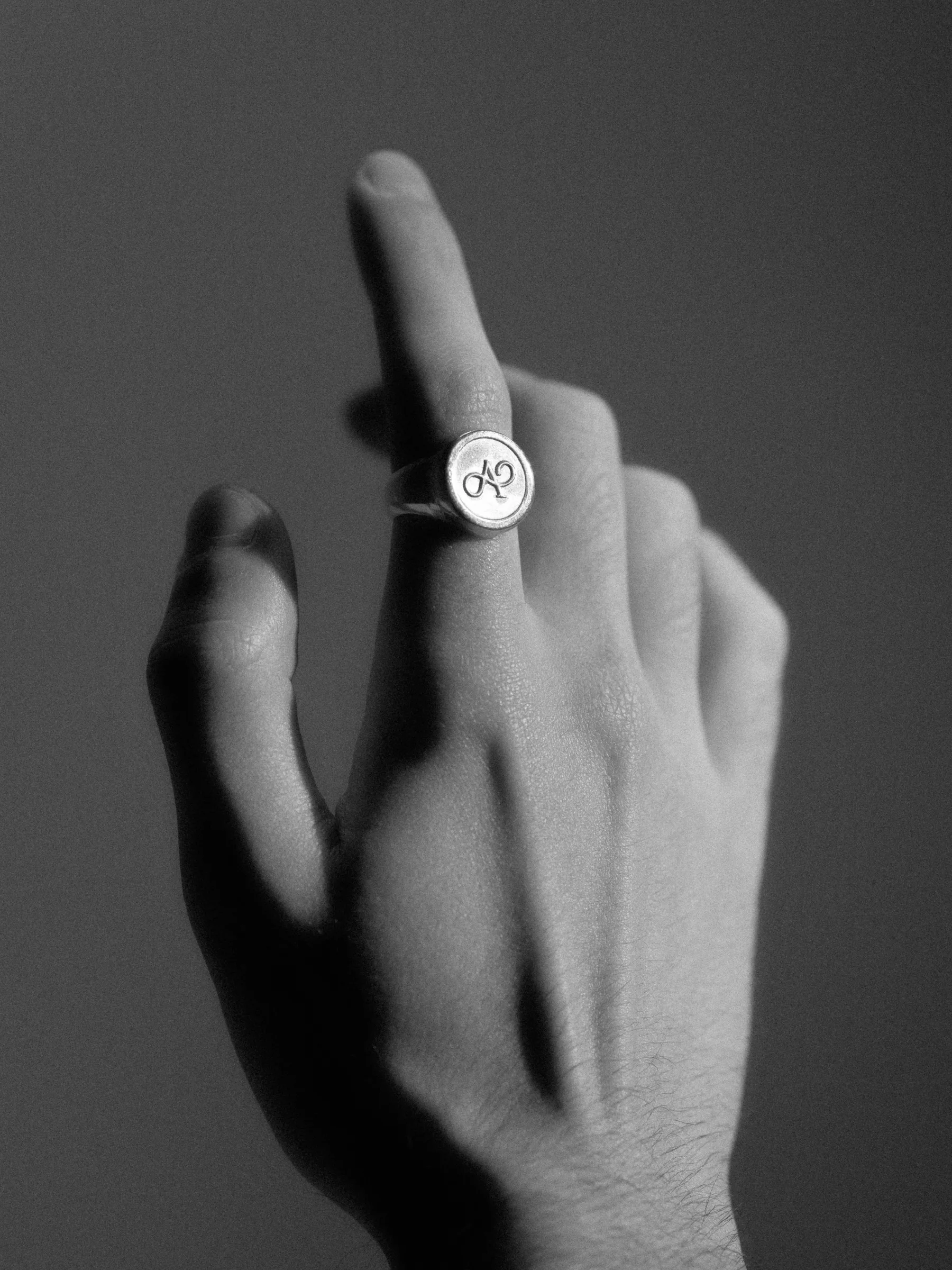 Hand wearing the Anagram signet ring, black and white